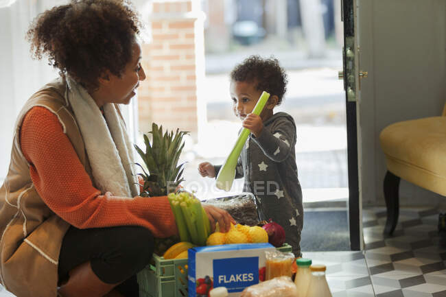 Carino bambino figlia aiutare la madre scaricare consegna della spesa — Foto stock