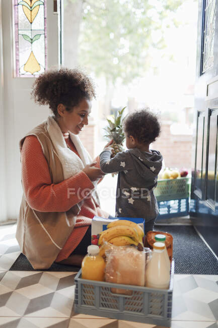 Baby-Tochter hilft Mutter beim Ausladen von Lebensmittellieferung vor Haustür — Stockfoto