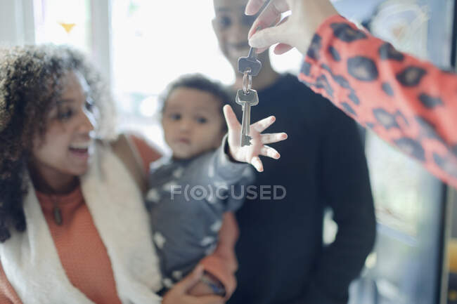Happy young family receiving new house keys from realtor — Stock Photo
