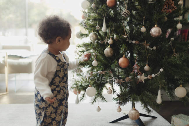 Cute baby girl looking at Christmas tree decorations — Stock Photo