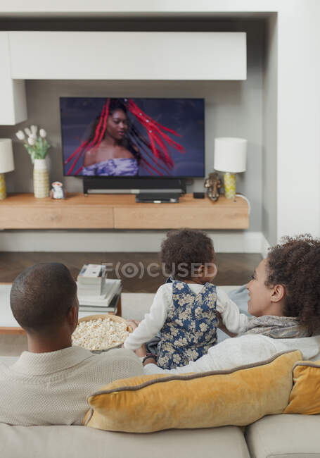 Сім'я дивитися телевізор на вітальні диван — стокове фото