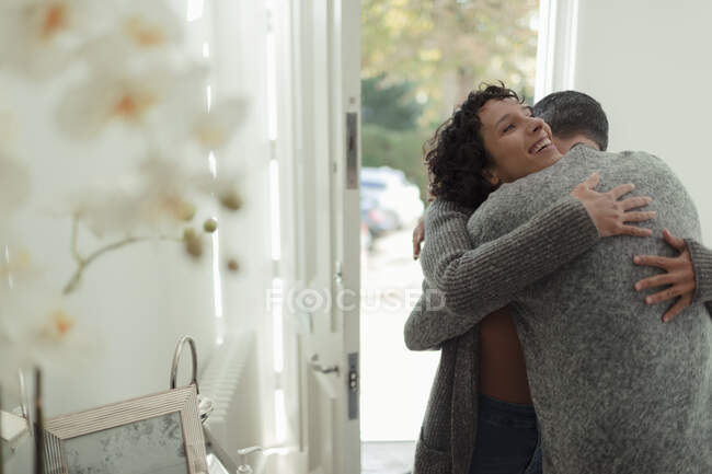 Feliz pareja cariñosa abrazándose en la puerta principal de la casa - foto de stock