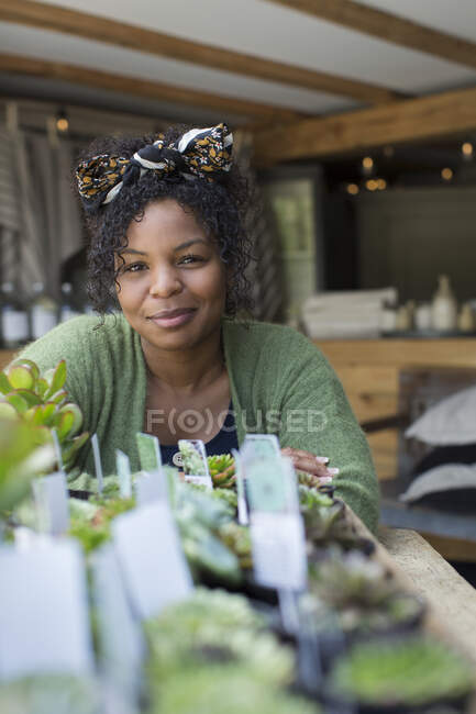 Portrait female shop owner at succulent display in plant nursery — Stock Photo