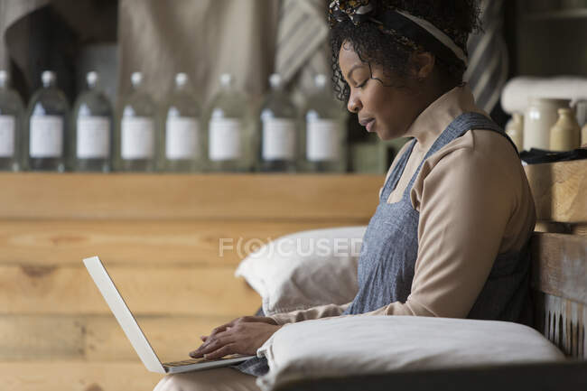 Female shop owner using laptop on bench — Stock Photo