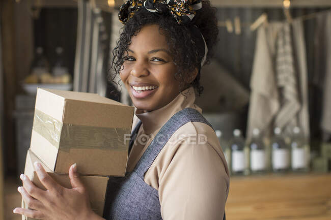 Portrait happy confident female shop owner with cardboard boxes — Stock Photo