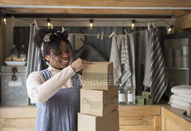Dono de loja feminino sorridente com pilha de caixas de papelão — Fotografia de Stock