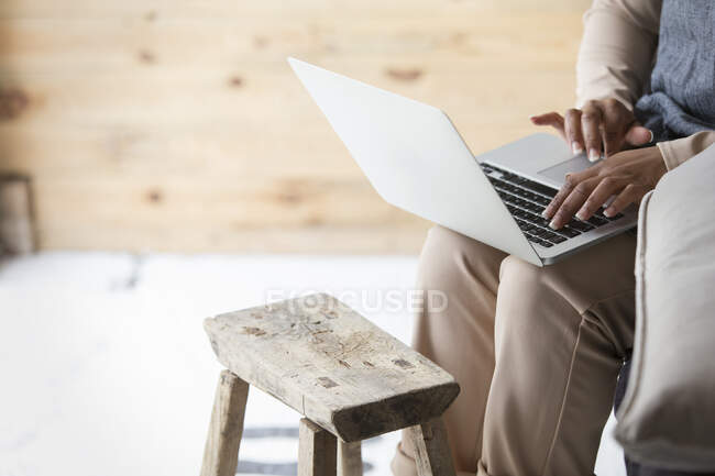 Proprietário da loja feminina usando laptop em banquinho de madeira — Fotografia de Stock