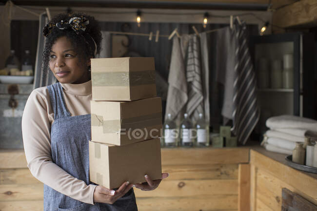 Portrait confident female shop owner with stack of cardboard boxes — Stock Photo