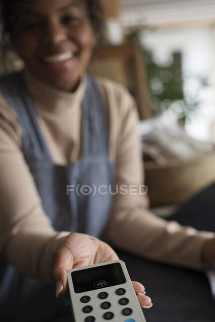 Власниця магазину POV жінка має читача кредитних карток для клієнта. — стокове фото