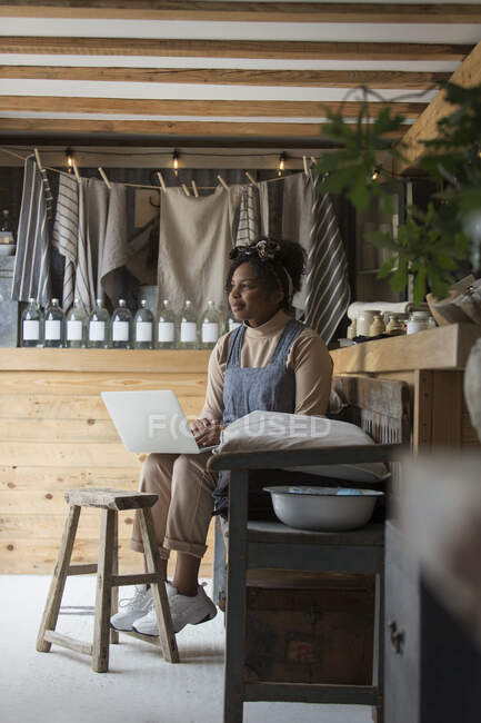 Pensativo propietario de la tienda femenina utilizando el ordenador portátil - foto de stock
