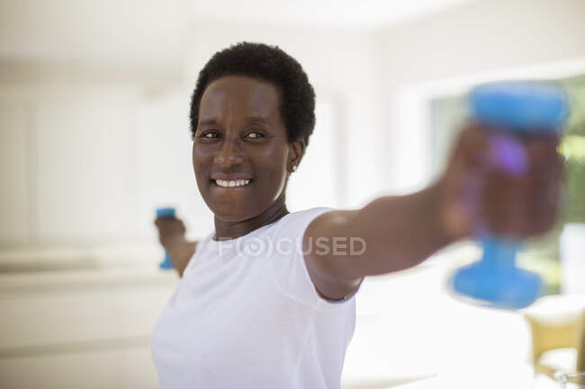 Mujer mayor confiada haciendo ejercicio con pesas - foto de stock