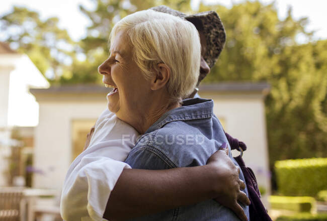 Happy senior women friends hugging on patio — Stock Photo
