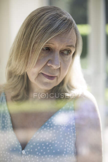 Продумана старша жінка дивиться через плече — стокове фото