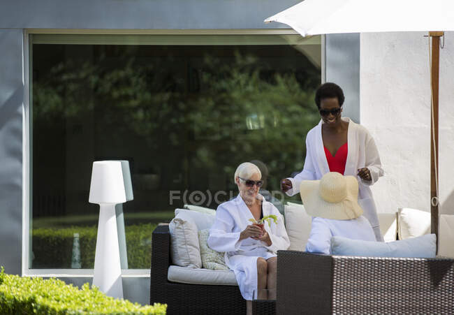 Senior women friends relaxing in spa bathrobes on luxury patio — Stock Photo
