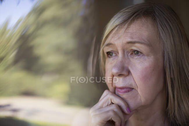 Nahaufnahme besorgte Seniorin schaut aus Fenster — Stockfoto