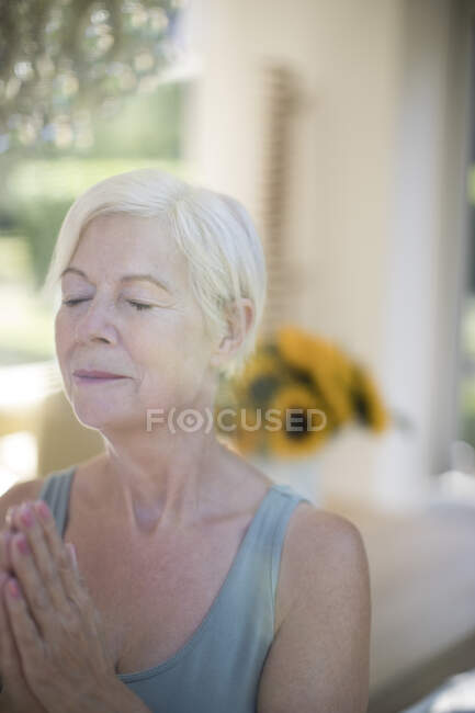 Serena mulher idosa meditando com os olhos fechados — Fotografia de Stock