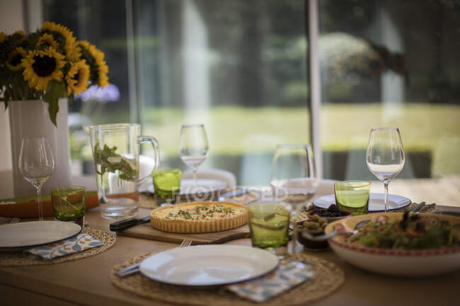Quiche and salad lunch on dining table with sunflowers — Stock Photo