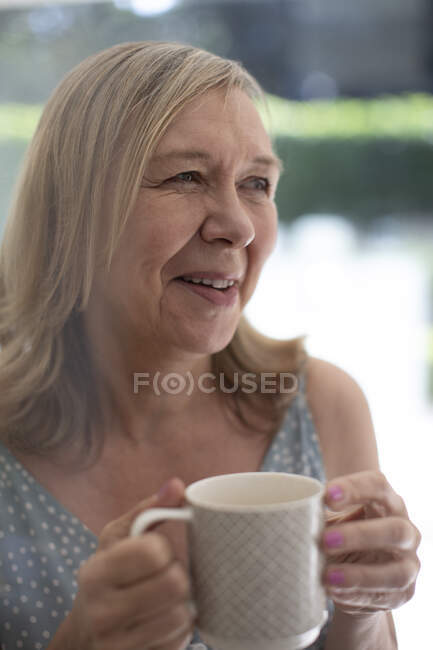 Щаслива старша жінка п'є чай — стокове фото