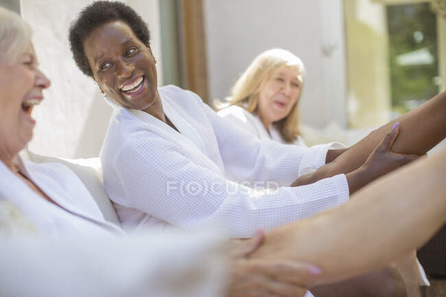 Verspielte Seniorinnen in Wellness-Bademänteln auf Hotelterrasse — Stockfoto