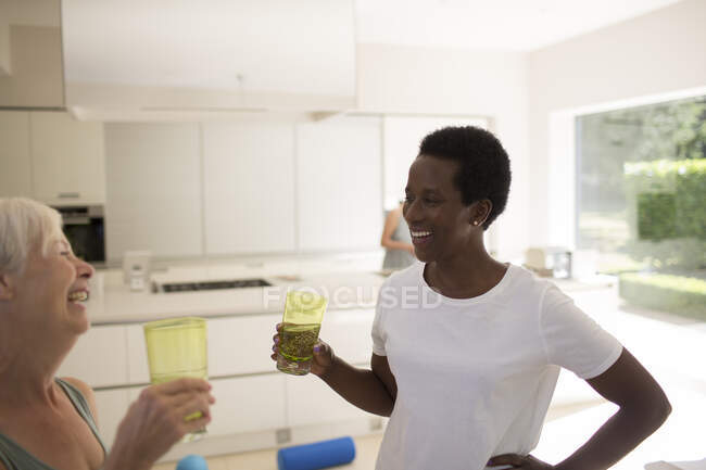 Happy senior women friends drinking water after exercising at home — Stock Photo