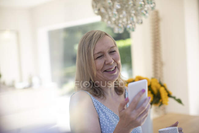 Sorridente donna anziana con smart phone a casa — Foto stock