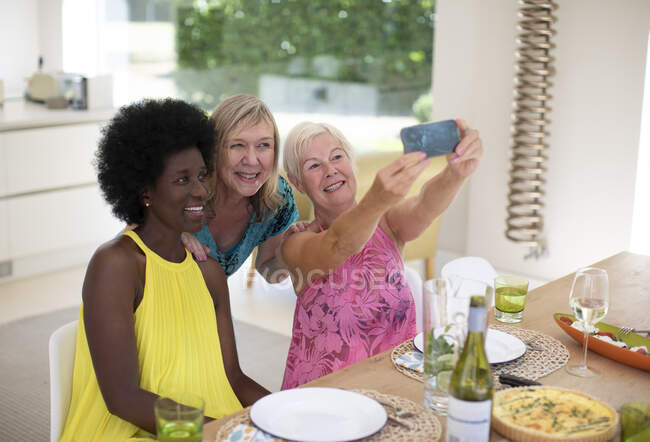 Felice anziane amiche prendendo selfie a pranzo — Foto stock