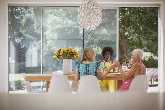 Happy senior women friends enjoying luncheon with wine at dining table — Stock Photo
