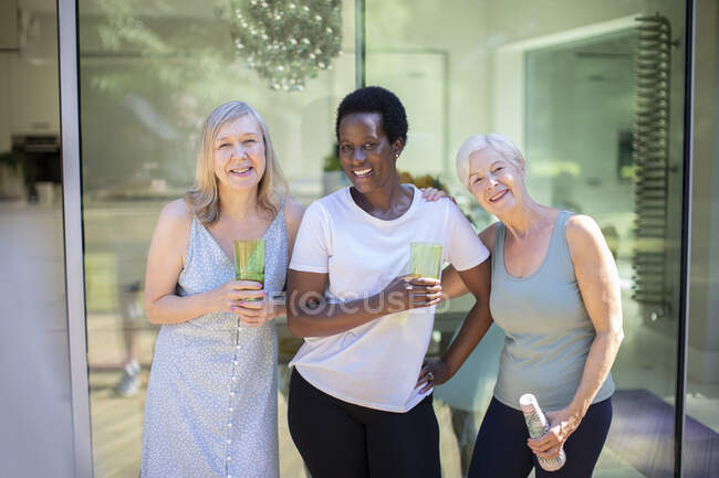 Portrait happy confident senior women drinking water on summer patio — Stock Photo