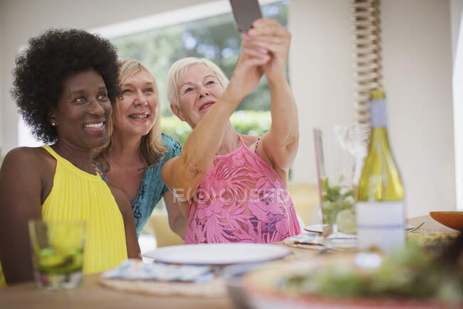 Літні жінки друзі приймають селфі за обіднім столом — стокове фото