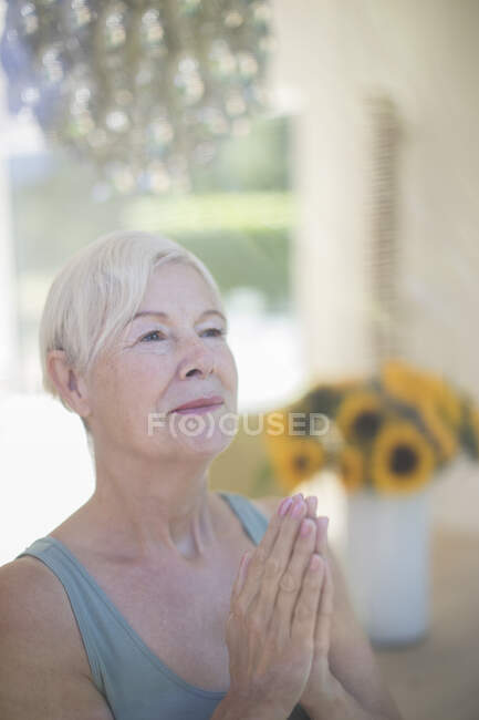 Serena mulher sênior meditando com as mãos apertadas — Fotografia de Stock