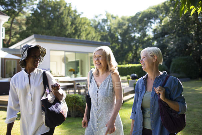 Senior women friends walking in sunny summer garden — Stock Photo