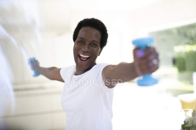 Retrato mulher madura enérgica exercitando com halteres em casa — Fotografia de Stock