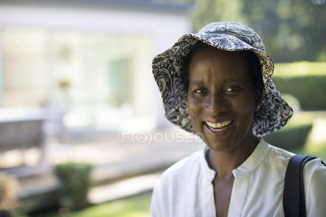 Portrait happy mature woman in sun hat in summer backyard — Stock Photo