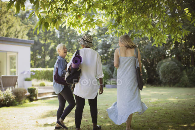Happy senior women friends with yoga mat in summer garden — Stock Photo