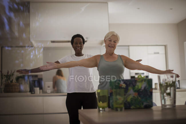 Mujeres mayores que hacen ejercicio en línea en el ordenador portátil en el comedor - foto de stock