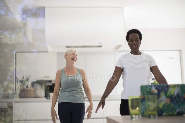 Mulheres seniores amigos exercitando on-line no laptop na cozinha — Fotografia de Stock