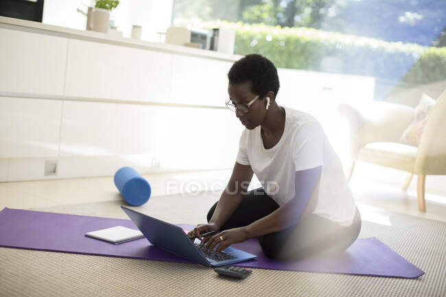 Mujer trabajando y ejercitándose en esterilla de yoga en casa - foto de stock
