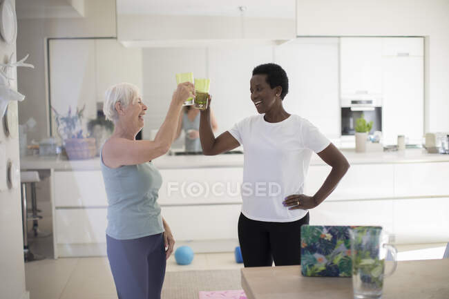 Счастливые пожилые подруги пьют воду после тренировки дома — стоковое фото