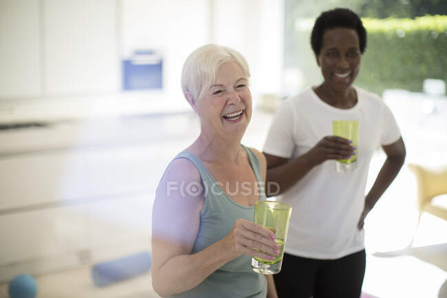 Glückliche Seniorinnen trinken nach dem Training zu Hause Wasser — Stockfoto