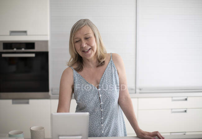 Femme âgée utilisant une tablette numérique dans la cuisine — Photo de stock