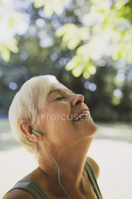 Fröhliche unbeschwerte Seniorin, die mit Kopfhörern Musik hört — Stockfoto