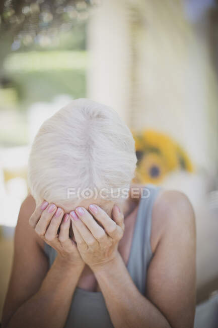 Stressed senior woman with head in hands — Stock Photo