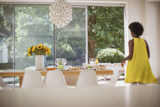 Femme en robe jaune mettant table à manger pour le déjeuner — Photo de stock