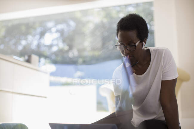 Fokussierte Frau mit Kopfhörer, die zu Hause am Laptop arbeitet — Stockfoto