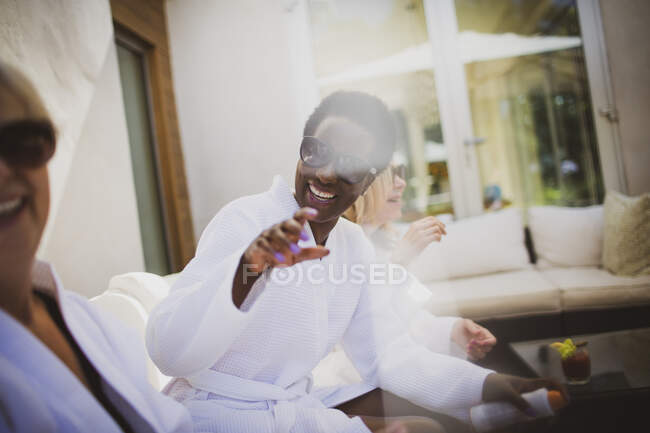 Happy senior women friends in spa robes and sunglasses on hotel patio — Stock Photo