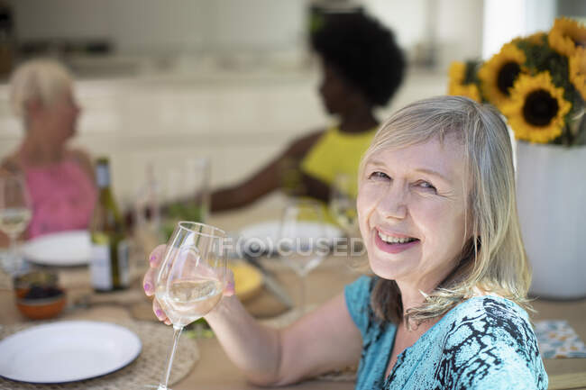 Porträt glückliche Seniorin trinkt Weißwein mit Freunden am Tisch — Stockfoto