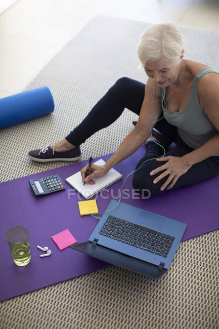 Seniorin arbeitet am Laptop auf Yogamatte — Stockfoto
