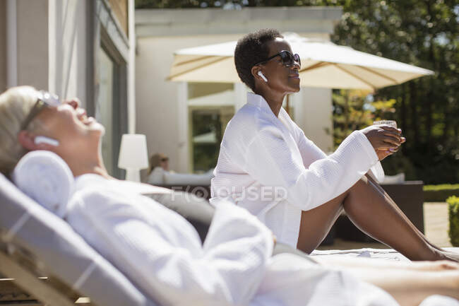 Unbekümmerte Seniorinnen in Wellness-Bademänteln entspannen auf sonniger Hotelterrasse — Stockfoto