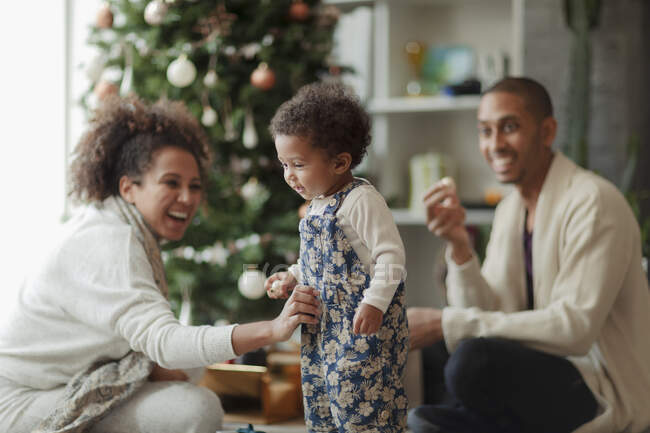 Genitori felici e bambina che decorano l'albero di Natale — Foto stock