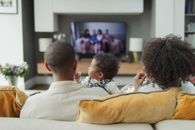 Eltern und kleine Tochter vor dem Fernseher auf dem Wohnzimmersofa — Stockfoto